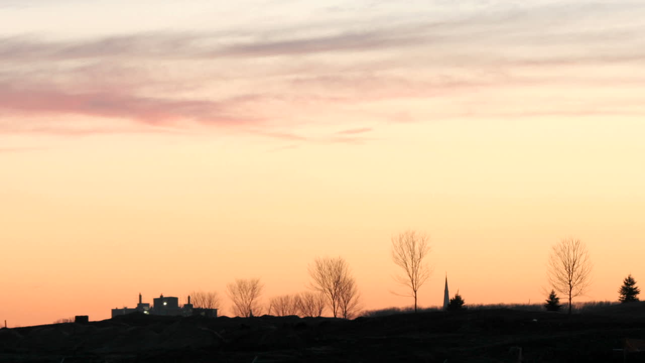 어두운 수평선 위로 생생한 하늘이 주황색 색조로 깊어짐에 따라 구름이 빨간색에서 검은색으로 변합니다.