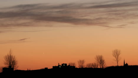 über-Einem-Dunklen-Horizont-Verfärben-Sich-Die-Wolken-Von-Rot-Zu-Schwarz,-Während-Sich-Der-Lebendige-Himmel-In-Orangen-Farbtönen-Vertieft