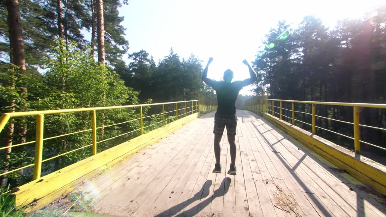 Man Celebrating on a Bridge in the Forest