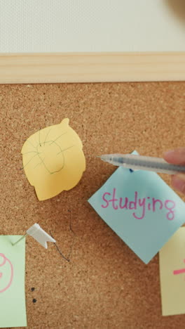 little boy draws sun on piece of colored paper in shape of leaf slow motion. child moves pen diligently. preschooler works with notes on cork board closeup