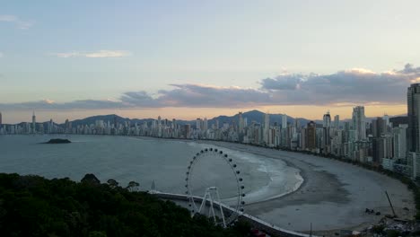 Luftaufnahme-Der-Stadt-Balneario-Camboriu-Bei-Sonnenuntergang-Mit-Dem-Riesenrad-Und-Hohen-Gebäuden