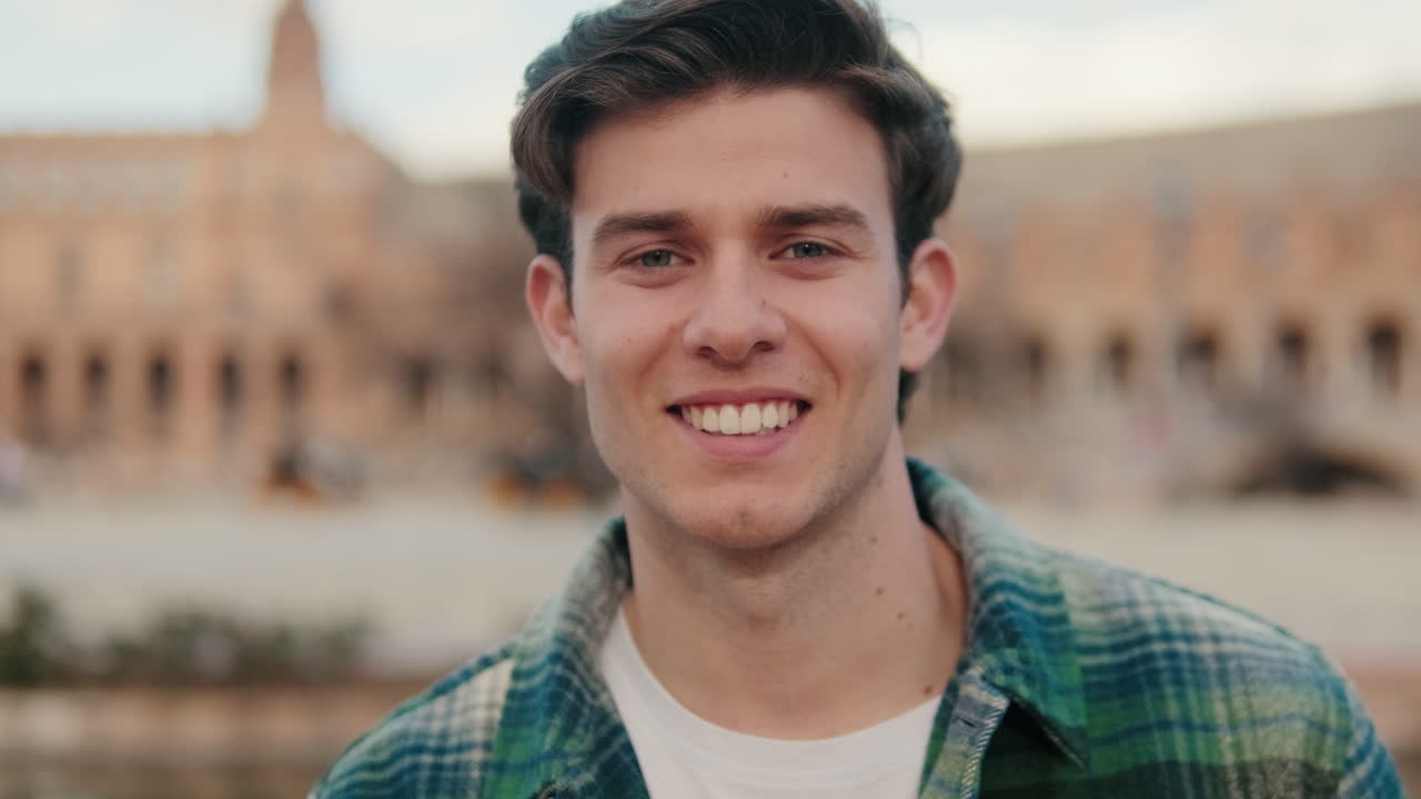 Close-up of young smiling man looking at camera on old city background