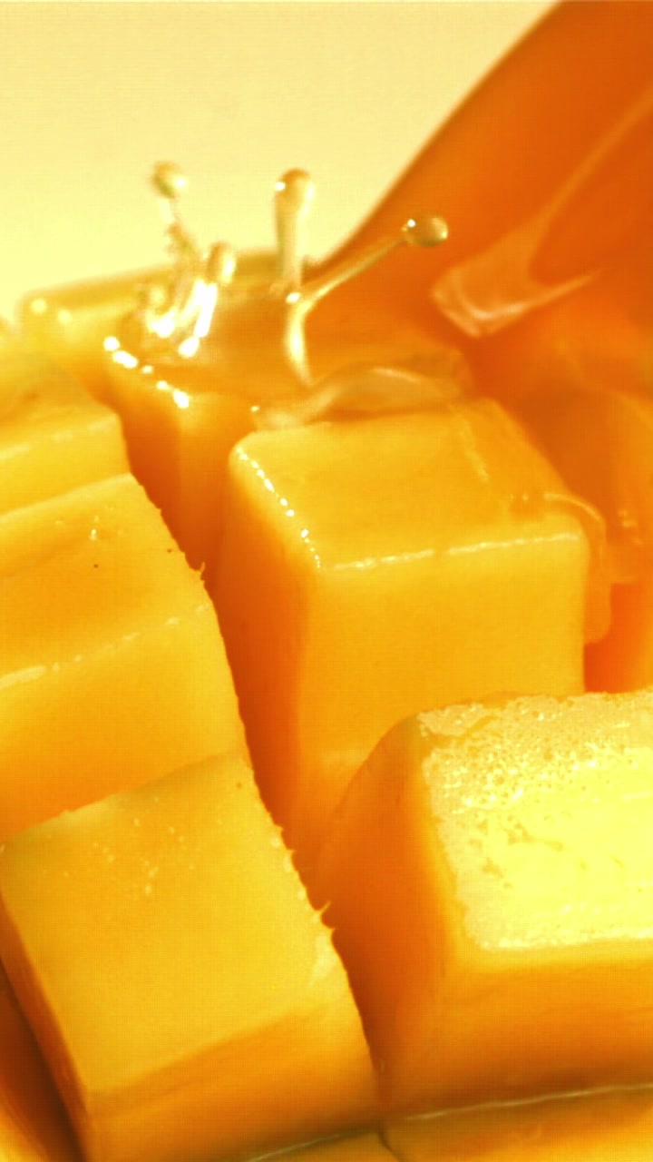 Miele dorato che cola su cubetti di mango fresco tagliato a dadini