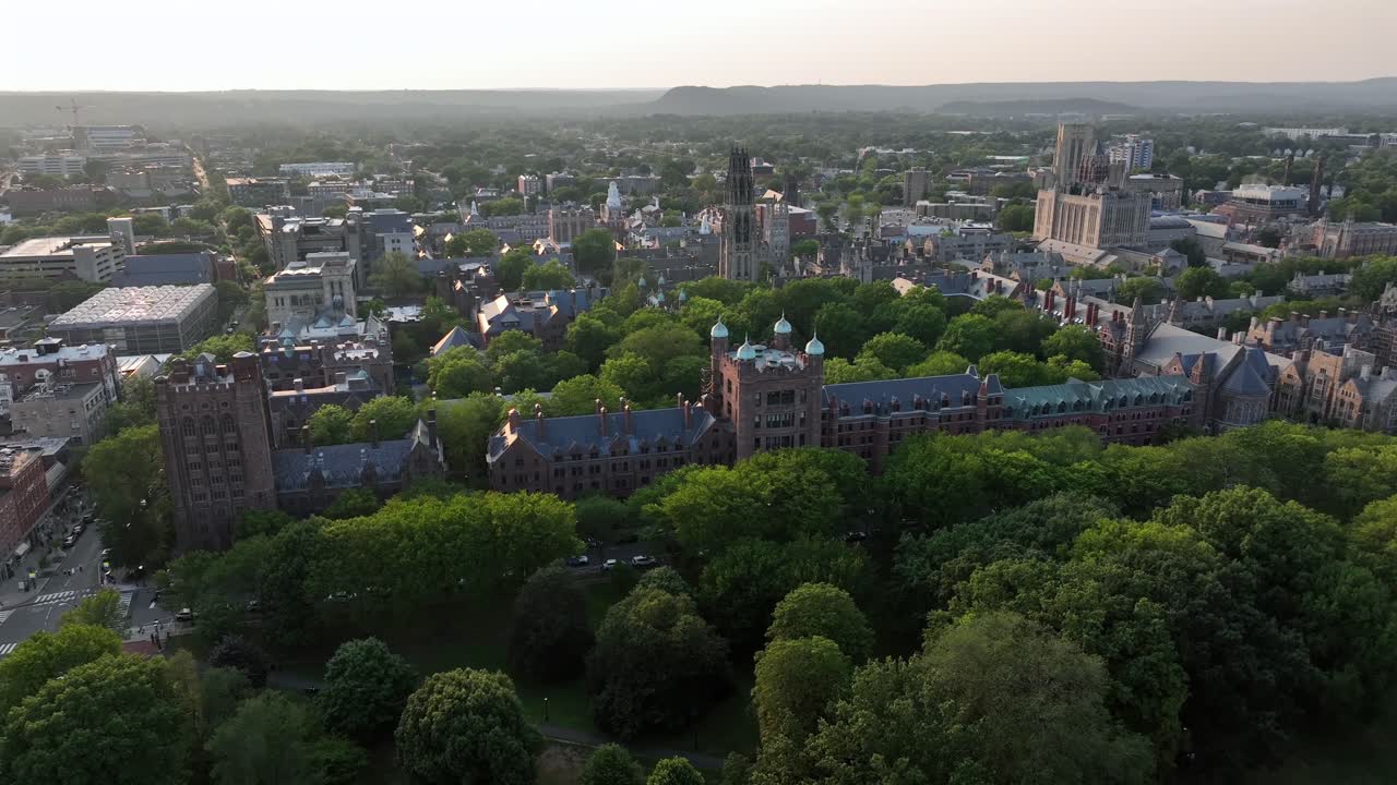 Yale university in gothic style during golden sunset in New Haven, Connecticut. Aerial wide shot. Green trees inside inner yard of campus