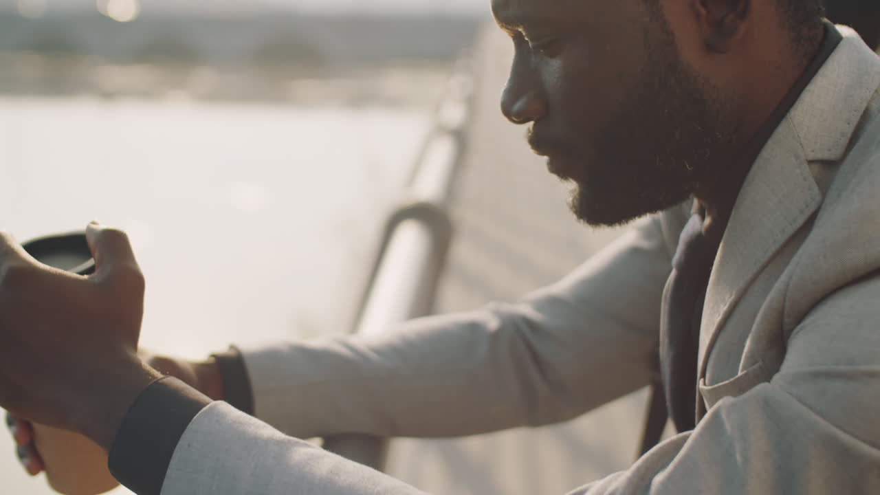 hombre de negocios afroamericano de pie con café en el terraplén