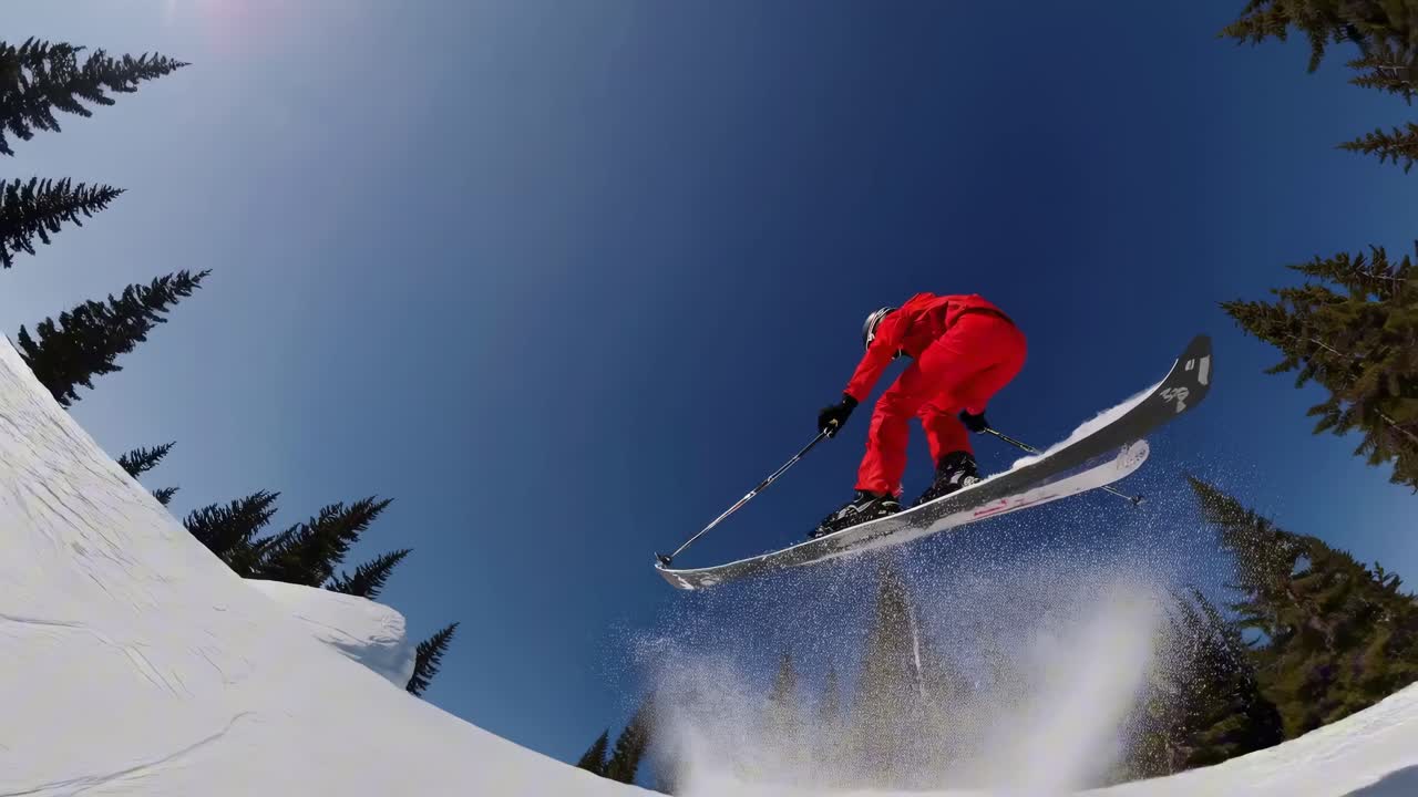 POV video of a skier in a red suit descending a snowy slope, surrounded by pine trees