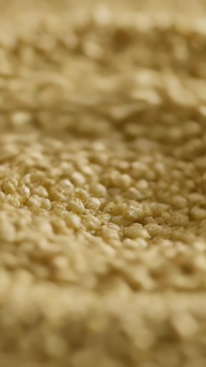 Video verticale: Messa a fuoco, telecamera che rivela couscous su un vassoio durante la preparazione del cibo, evidenziando la consistenza