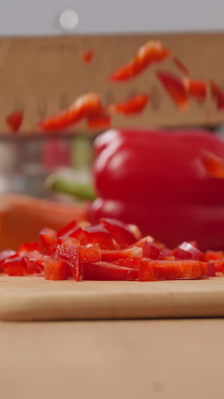Housewife cuts fresh red bell pepper on wooden board with big knife on blurred background. Woman cooks delicious salad for breakfast in kitchen closeup