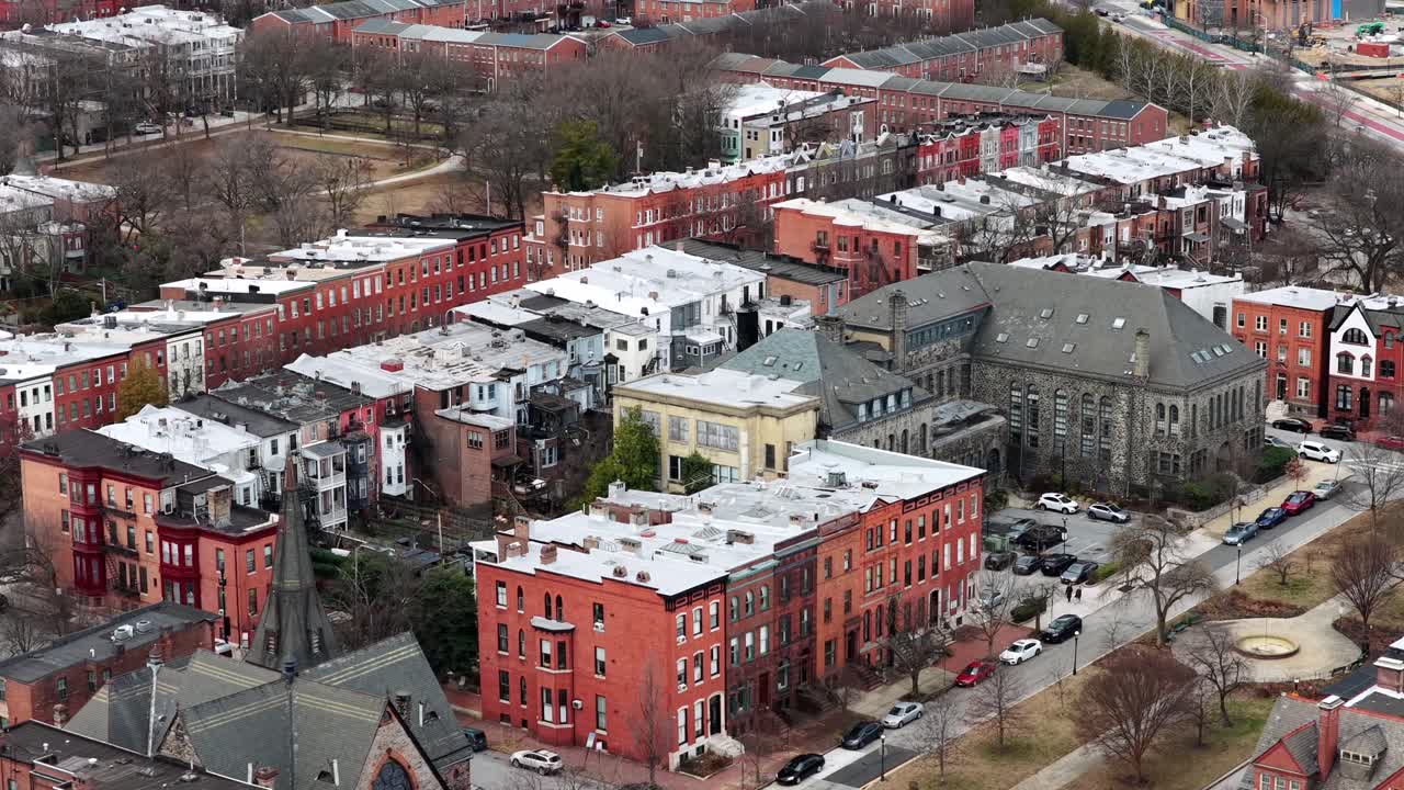 Vista aérea del barrio de Bolton Hill en Baltimore, Maryland, con históricas casas adosadas de ladrillo rojo, un campanario de iglesia, tejados invernales y calles residenciales bajo una suave luz estacional. Escena tranquila en EE. UU.