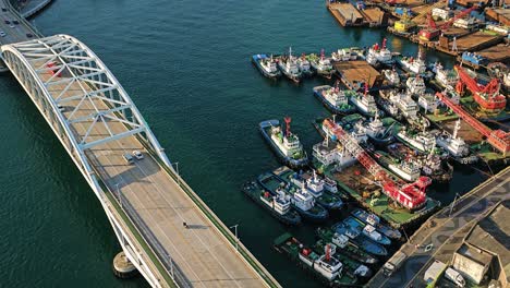 traffic on busan bridge towers over a bustling port filled with ships and cranes in busan, south korea, seen from above - slow pan