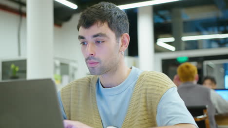 young handsome man typing on laptop in the office