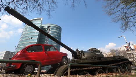 Viejo-Coche-Y-Tanque-Artístico-Guerra-Monumento-Con-Un-Fondo-De-Cielo-Azul-Lapso-De-Tiempo-Estático-Cerca-De-ángulo-Bajo-Osijek,-Croacia