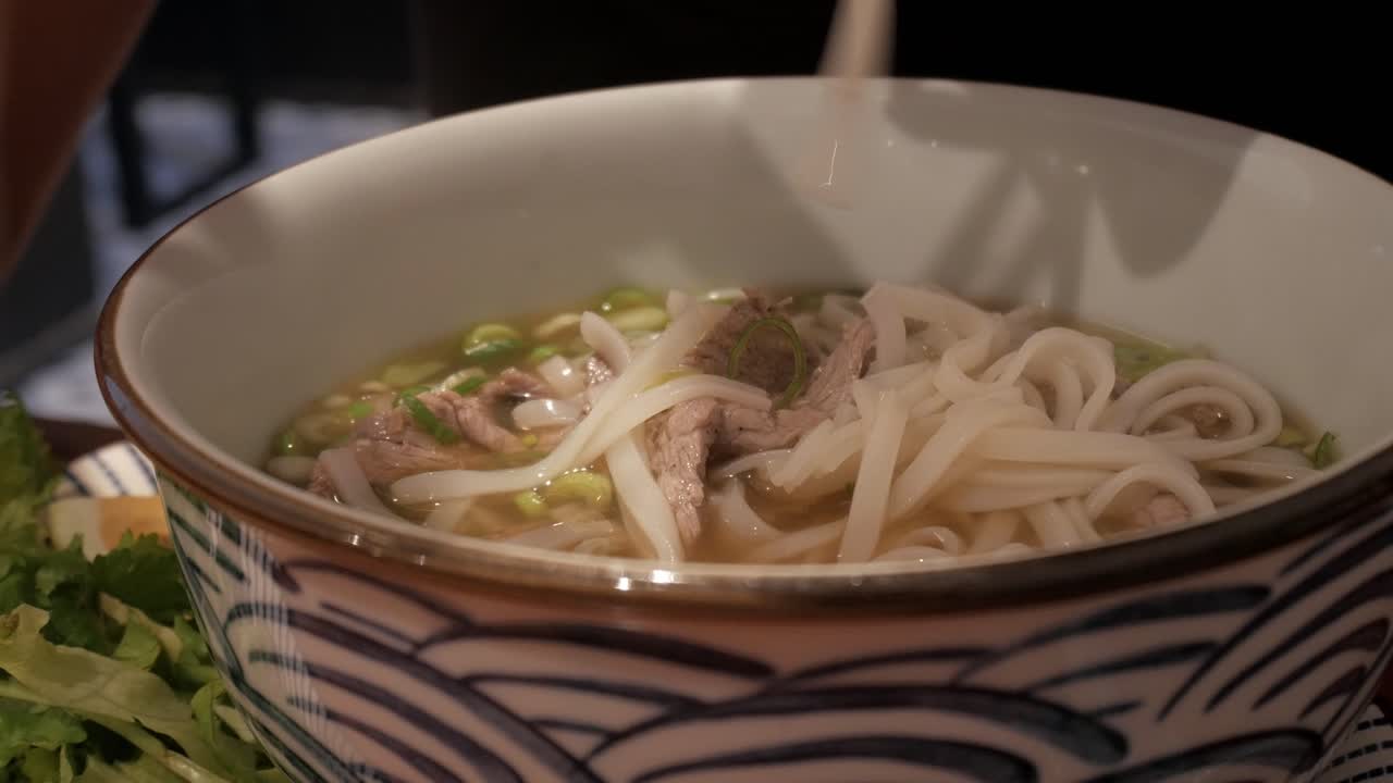 Freshly prepared Pho Bo noodles served in a bowl with beef, herbs, and garnishes