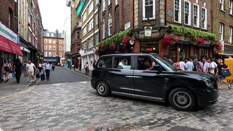 crowded street with pedestrians and a black taxi