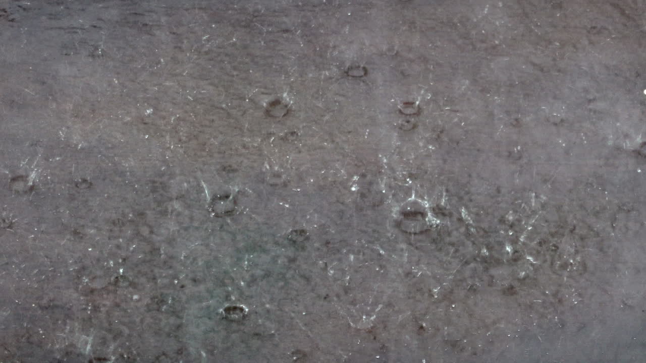 Raindrops splashing in a puddle during a torrential rainstorm in monsoon season.