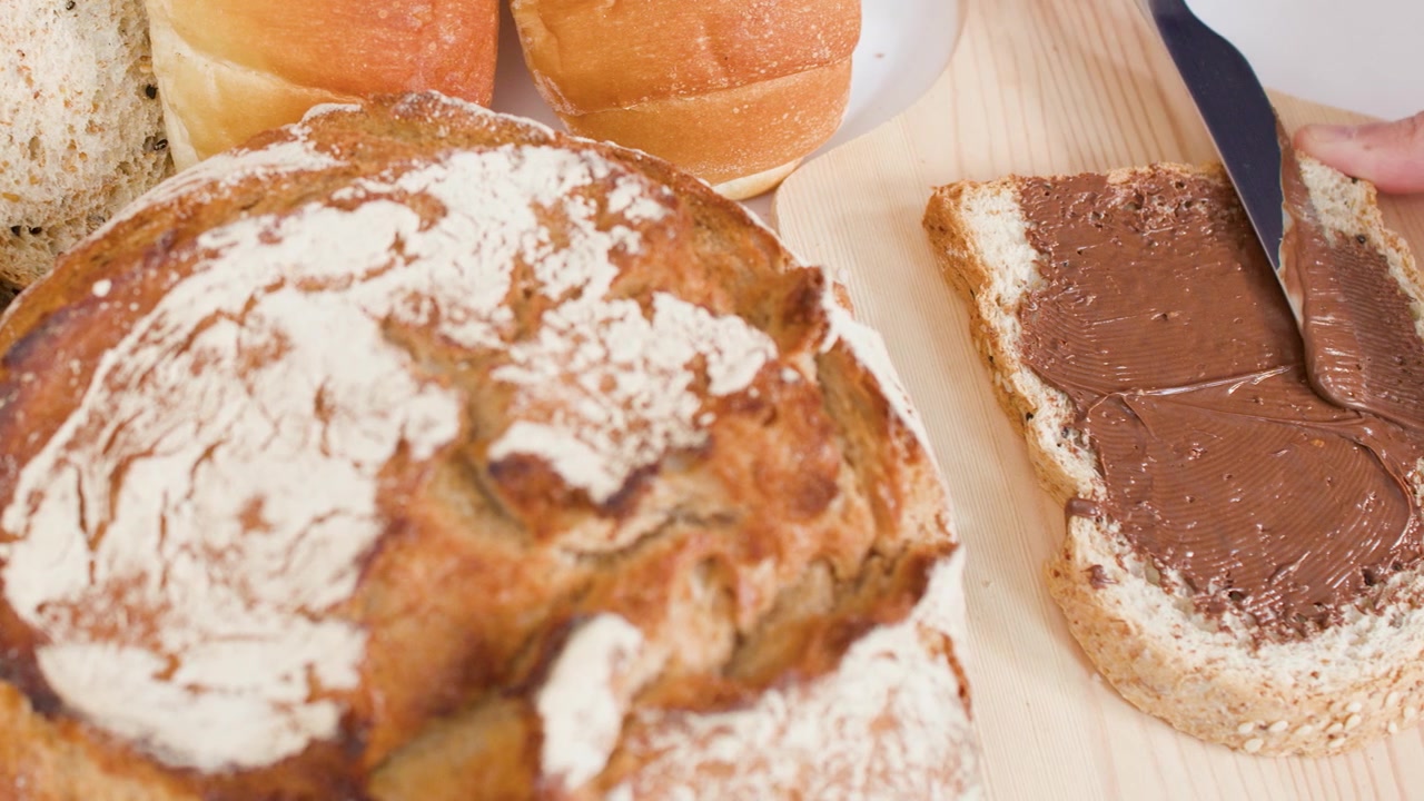 Spreading Chocolate Hazelnut Spread on a Slice of Whole Grain Bread