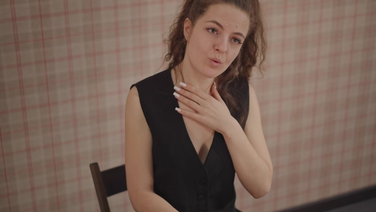 Musicista caucasico che suona il pianoforte e canta in un'accogliente sala prove, mani sulla tastiera, inquadratura a mezzo busto con sfondo di carta da parati a fantasia, cantautore concentrato che prova accordi e melodia, viso espressivo.
