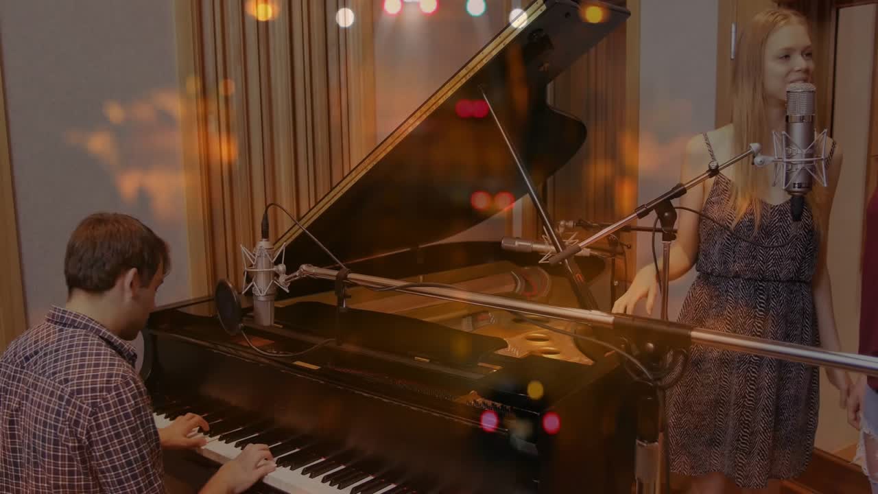 Pianista che suona un pianoforte a coda fa cantare in armonia dei vocalisti durante una sessione di registrazione.