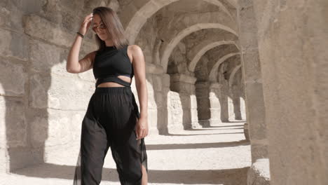 young woman walking in archway of ancient greek roman historic site, revealing shot