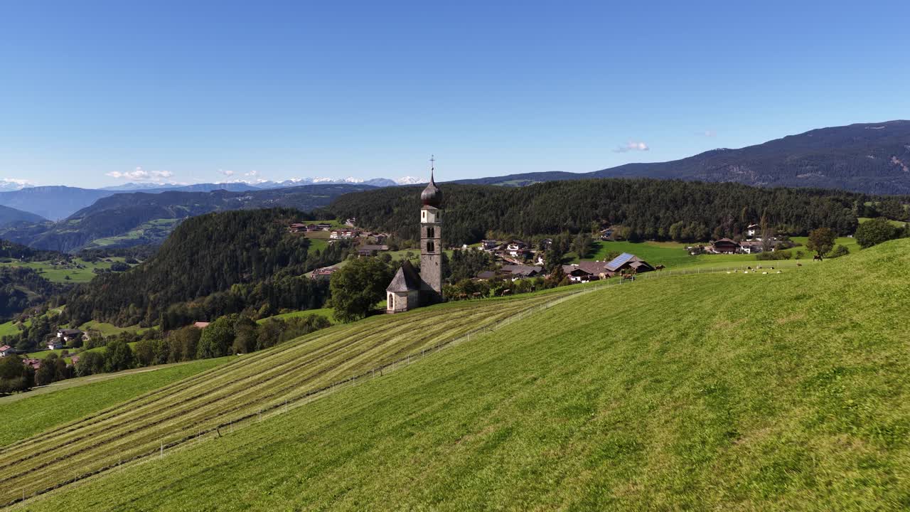Small church, chiesa in the Italian dolomites. Alpine fields, agricultural grass lands. Aerial video