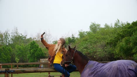 woman taking selfie with horse on wooden fence 4k