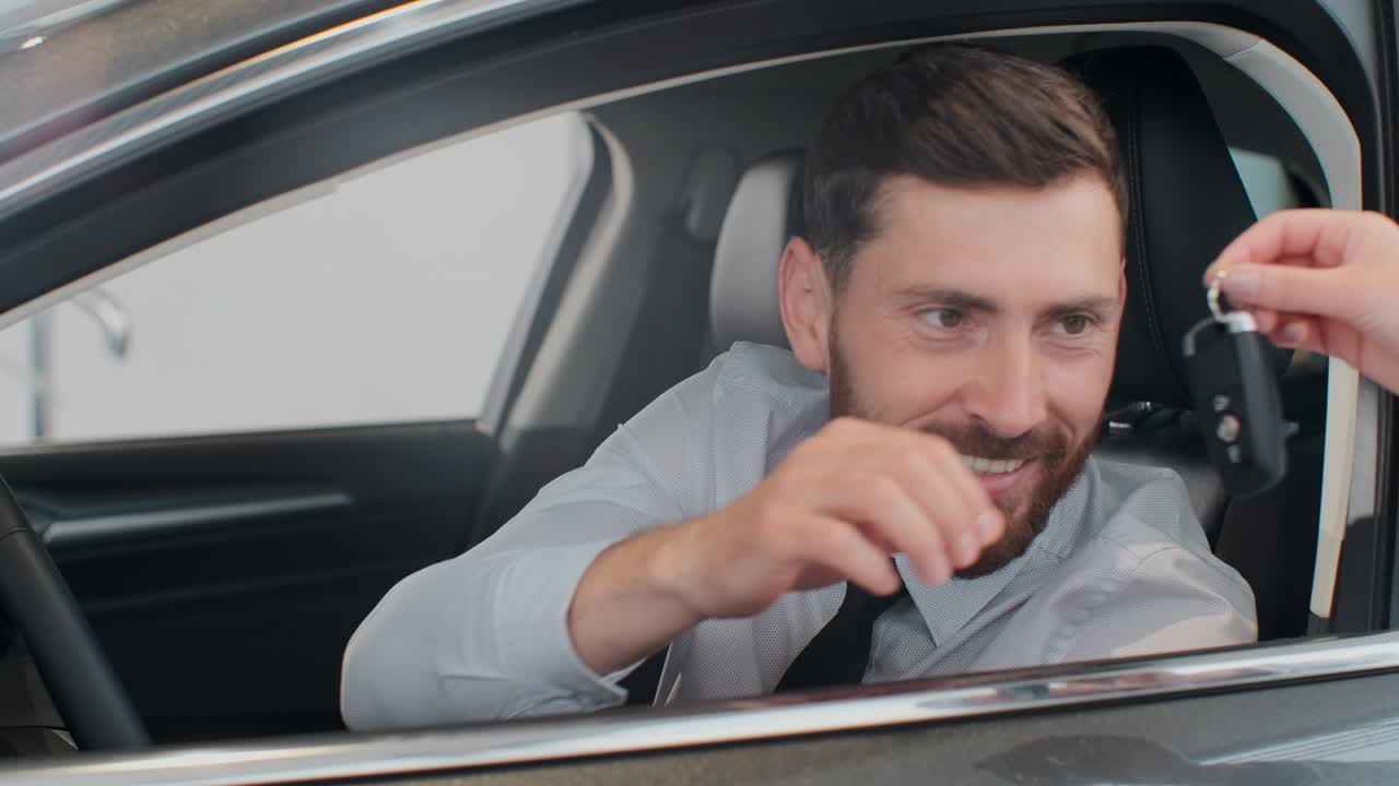 Sales manager handing over the keys to man that sitting in the car.