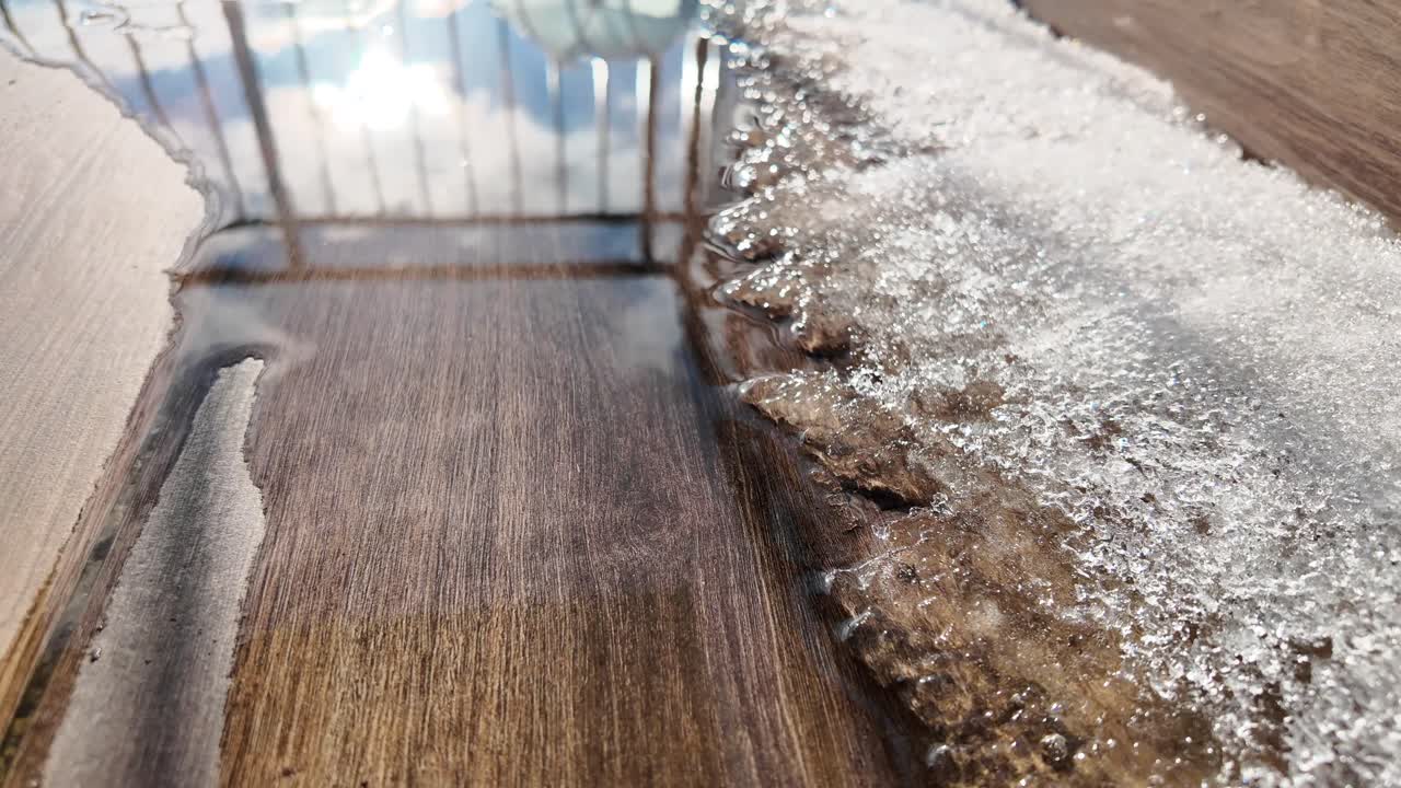 Melting Snow and Ice on a Wooden Surface with Sky Reflection