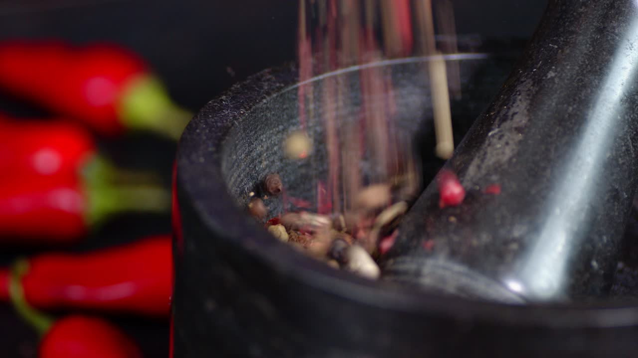 granos de pimienta cayendo en el mortero con un pestillo.