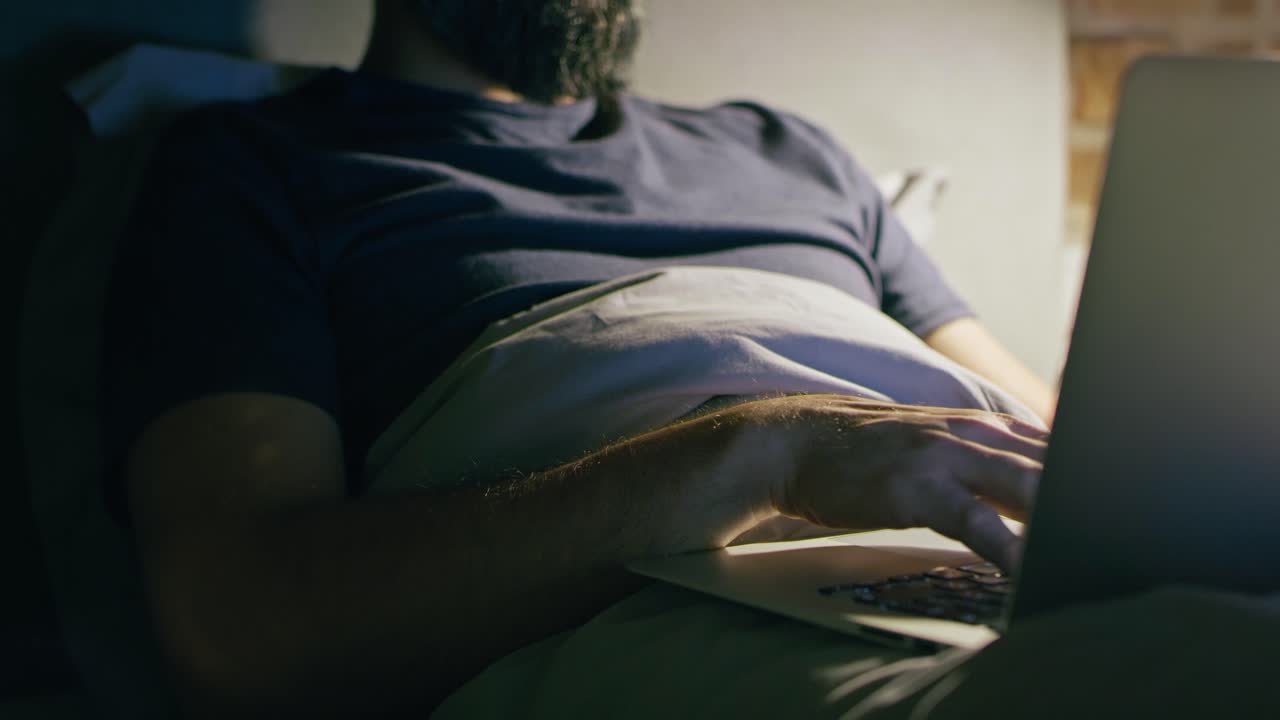 Tilt up video of man lying and working in bed