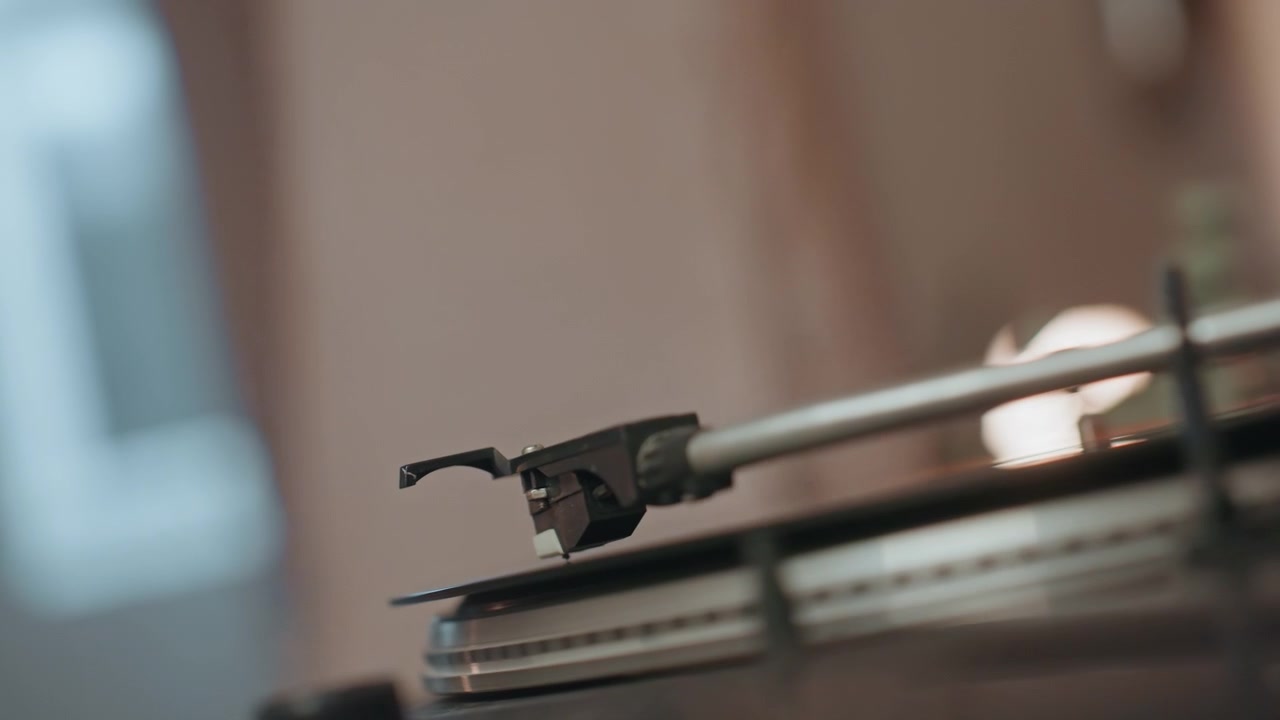 Gentle glow illuminating tactile record grooves. Nostalgic scene capturing stylus interacting with vinyl surface. Warm ambient light emphasizing intimacy of analog record playing experience
