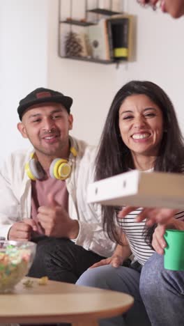joyful friends cheering and sharing food at home