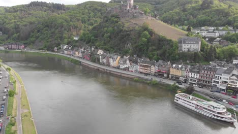 static establishing shot over the moselle river as a cruise ships docked at the city of cochem, popular tourist destination in europe, germany