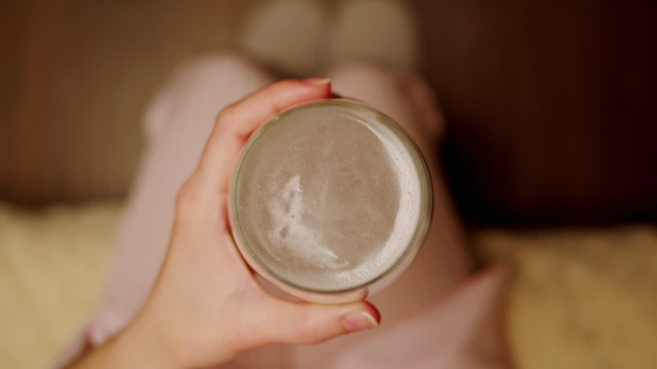 mujer sentada en el sofá sosteniendo un vaso de cerveza