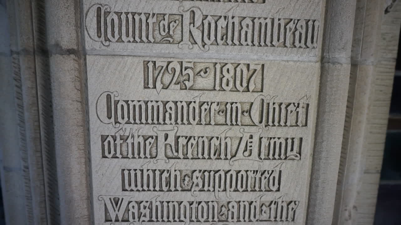 Camera tilts down on gothic script engraving on stone wall expressing a patriotic and religious message