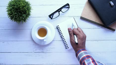 person writing in notebook on a desk