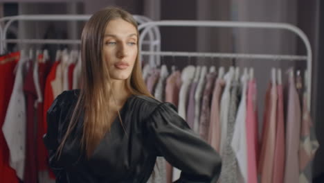 Hermosa-Chica-Con-Un-Vestido-Negro-Se-Mira-En-El-Espejo-De-La-Tienda.-Probándose-Un-Vestido-De-Noche.