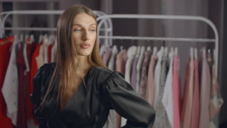 una hermosa chica con un vestido negro se mira en el espejo en la tienda. probando un vestido de noche.