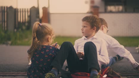 boy throws textbook with friend and little girl on pavement