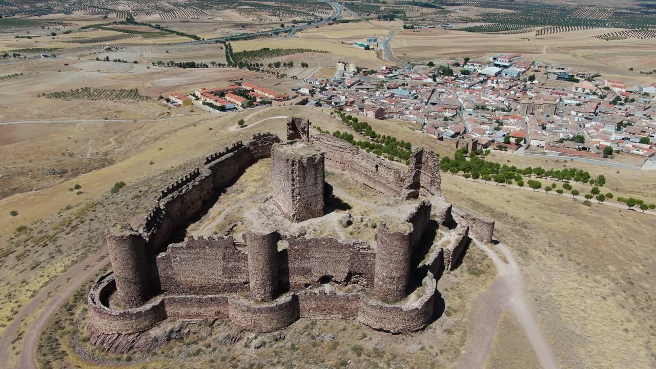 vuelo oral en un castillo en ruinas con sus muros y torres en una colina viendo que la torre principal está en el medio de la fortaleza y con campos de cultivo y una ciudad en un día de verano en toledo españa