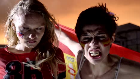 portrait of two young girls, football fans in the rain, england and spain, screaming, stadium in the background 50 fps