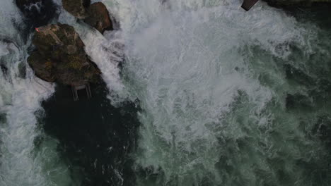 Toma-Aérea-Sobre-Las-Cataratas-Y-Rocas-Del-Río-Rin-Y-Donde-Se-Puede-Ver-La-Bandera-Suiza