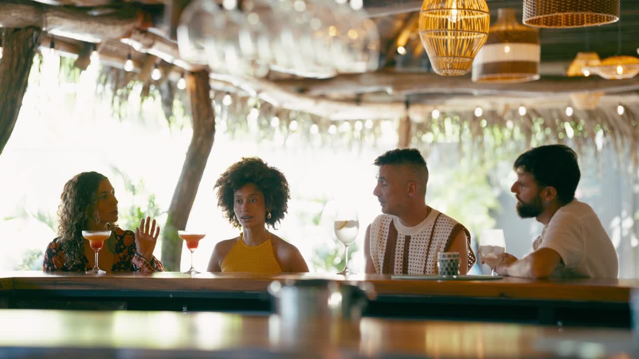 Group of Friends Socializing and Drinking Cocktails at a Tropical Bar