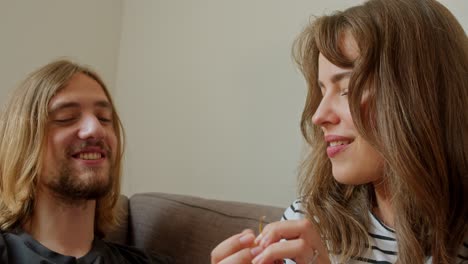 a woman is playfully teasing a man with grapes while sitting on the couch - close up