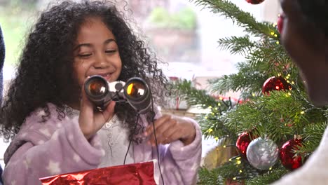 girl unwrapping binoculars at christmas