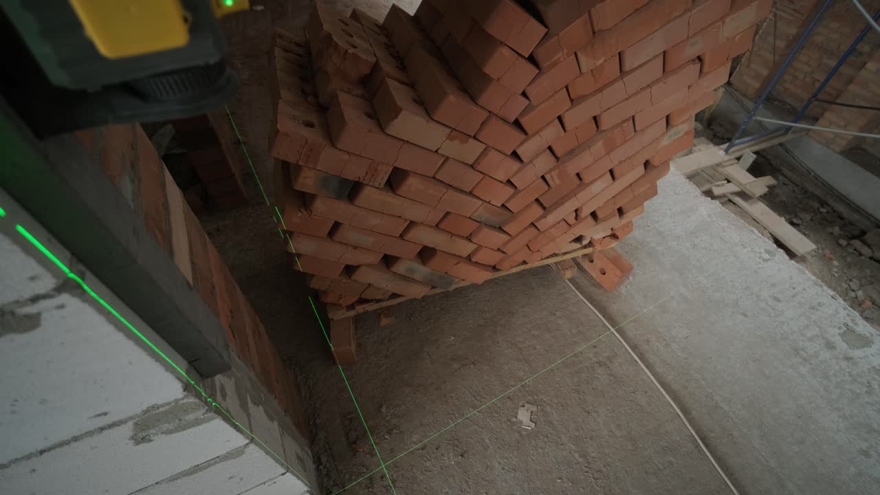 건설자는 녹색 레이저 레벨을 사용하여 수리 라인을 측정합니다.