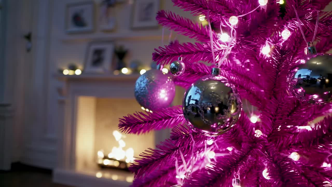 Close-up video of a vibrant pink Christmas tree with silver ornaments, shot from a side angle