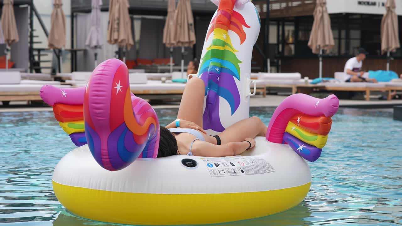 mujer relajándose en un flotador de piscina unicornio