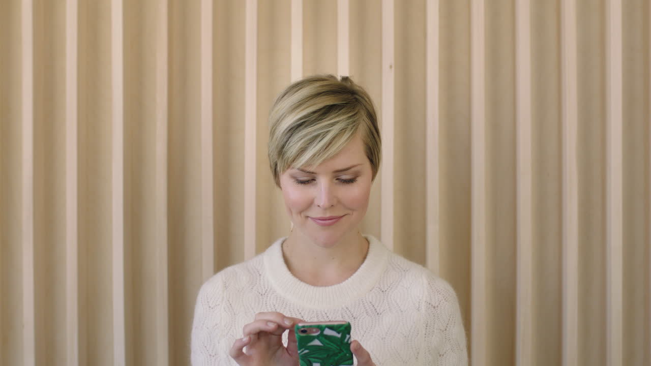 스마트폰 모바일 기술을 사용하여 문자 메시지를 집중적으로 검색하는 우아한 젊은 금발 여성의 초상화