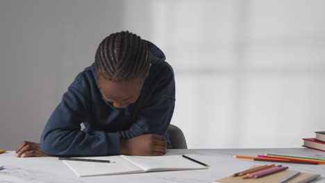 Studio-Shot-Of-Boy-At-Table-Struggling-To-Concentrate-On-School-Book-2