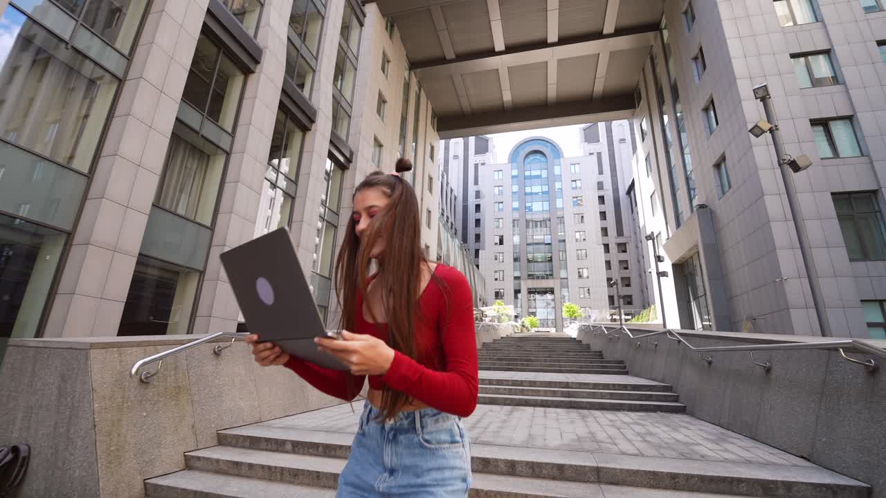 Mujer joven con portátil en escaleras de la ciudad